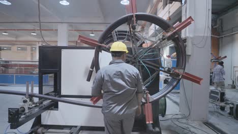 back view of a worker rotating machine wheel to be used in pvc pipe making factory in karachi, pakistan.