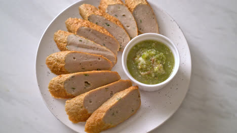 fried chinese fish cake or fish ball line sliced with spicy seafood dipping sauce