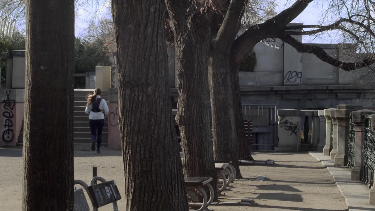 외로운 조깅하는 사람이 달리는 벤치가 줄지어 있는 텅 빈 봄 공원의 점심 시간 분위기