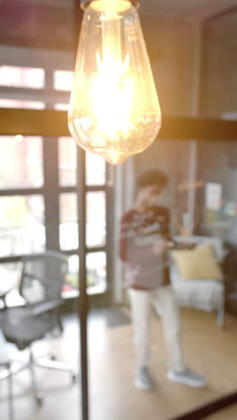 vertical video of african american man taking notes on glassboard at home, slow motion