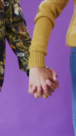 video vertical de la sección media de una pareja feliz y diversa tomándose de la mano