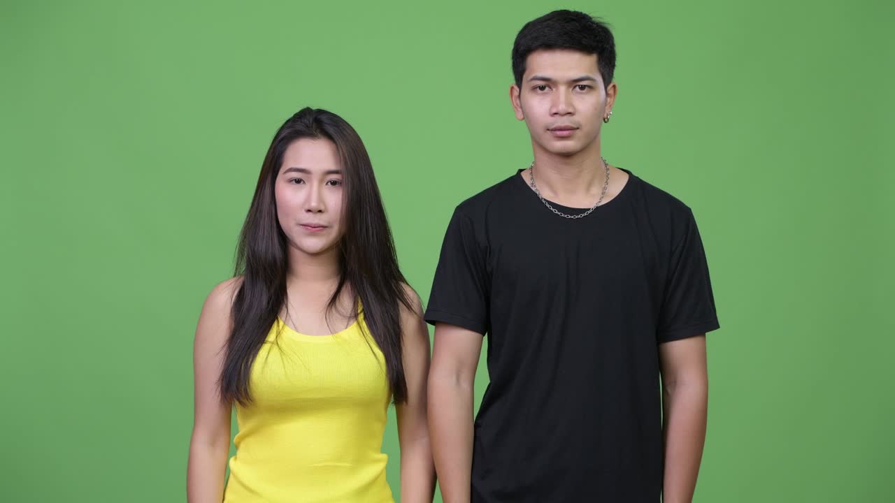 Young Asian couple pointing up together