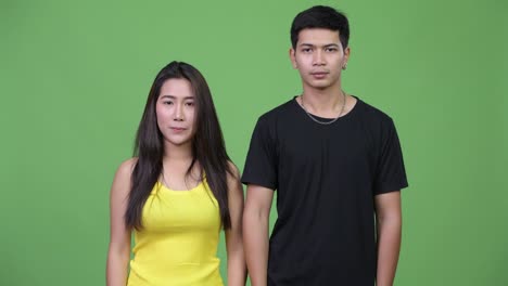 young asian couple pointing up together