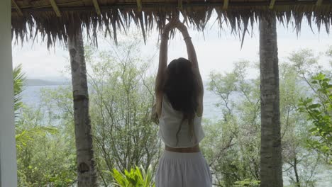 woman doing morning stretches on tropical hotel terrace overlooking the sea