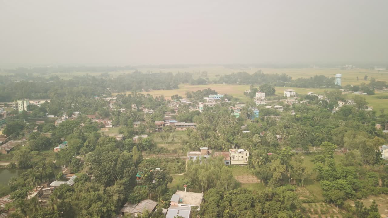 Birdseye drone shot reveals scattered homes and dense trees in a peaceful Bangladeshi village.