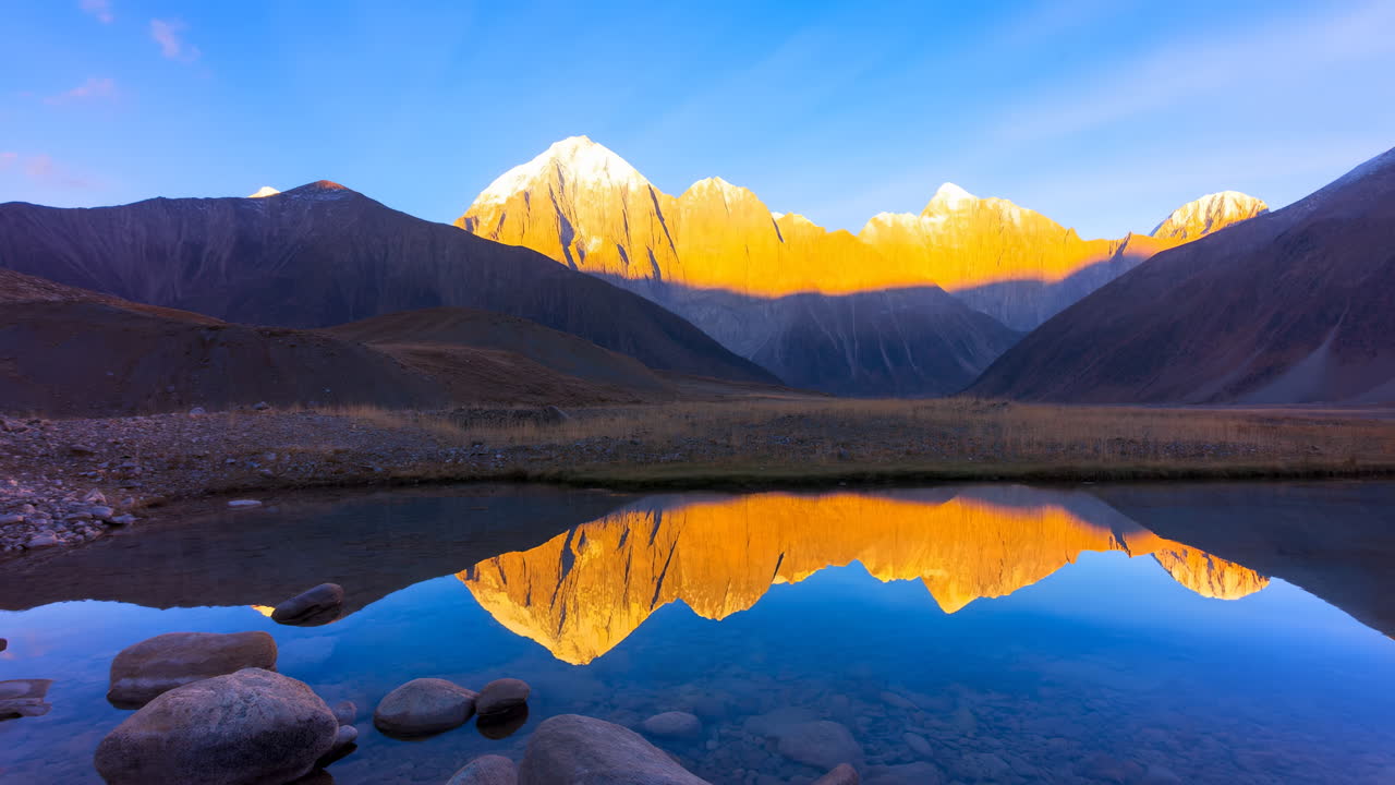 Time-lapse di un'alba dorata su una montagna maestosa riflessa in un lago
