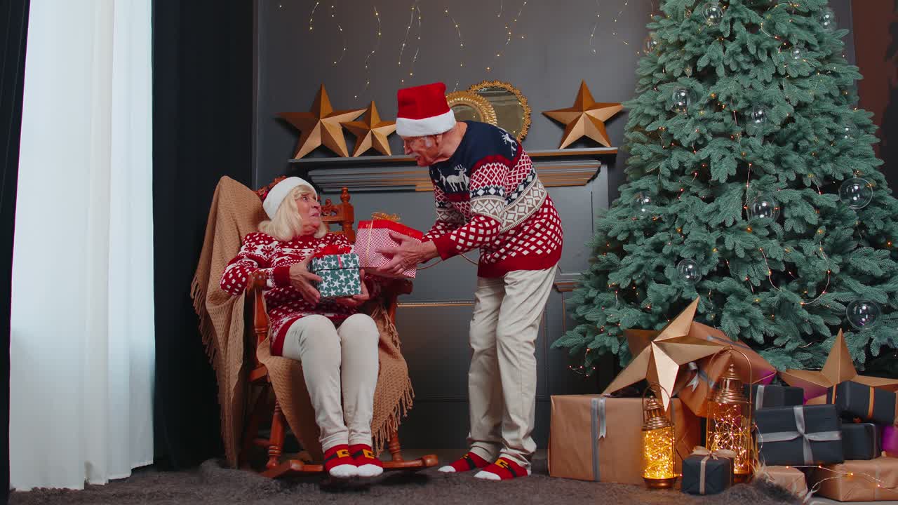 una pareja de ancianos de la familia, una abuela y una abuela, se presentan cajas de regalos de navidad en casa.