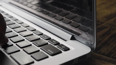 esquina del teclado del portátil con los dedos escribiendo parcialmente visible