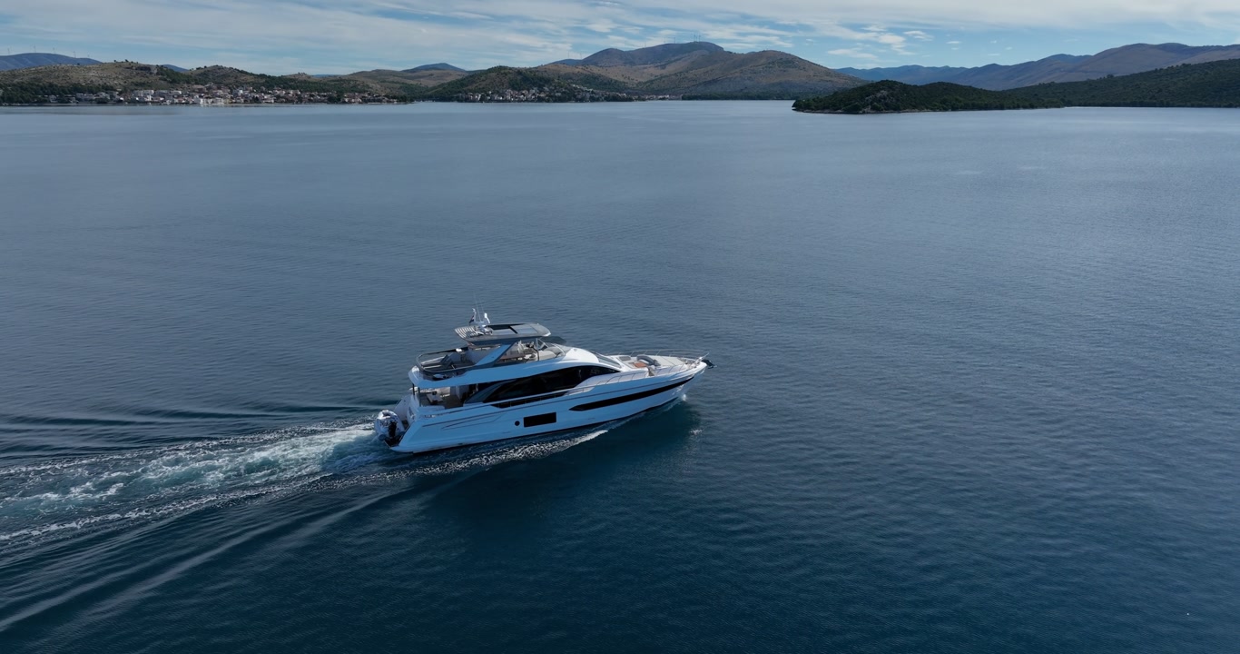 Modern white luxury yacht sailing on blue water with the scenic Dalmatian coast and mountains of Sibenik, Croatia in the background. High-end nautical lifestyle and Mediterranean summer travel.