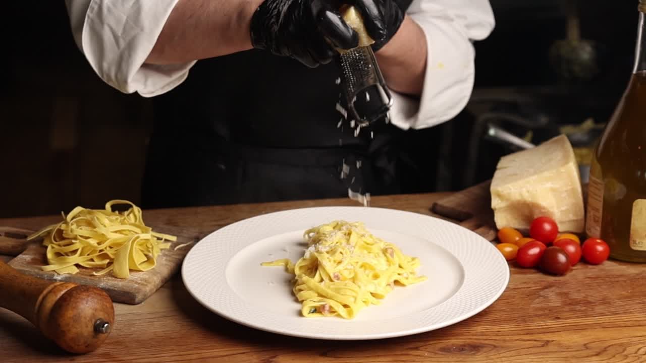 Chef che grattugia Parmigiano sulla pasta appena cotta