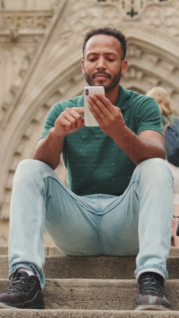 Uomo che usa il cellulare mentre è seduto sulle scale
