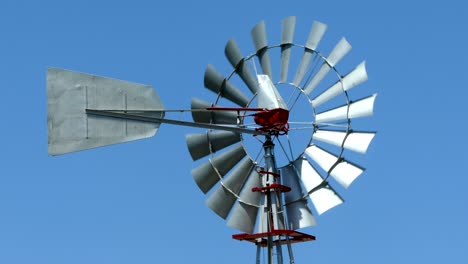 old vintage style windmill rotating on a sunny day with blue sky background.