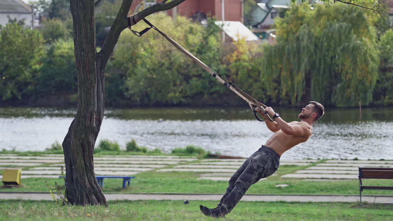 Training in open air. Young man working out by the lake in city park