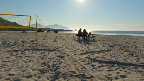 two tourist enjoying the view at flakstad beach, having lunch next to beachvolleyball net