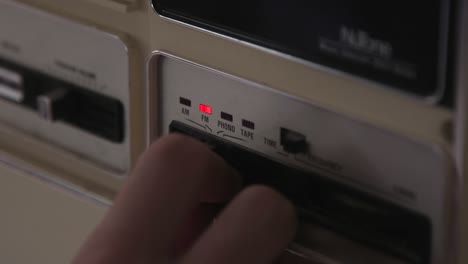 a hand reaches in pushing the choice indicator on an intercom from tape to fm