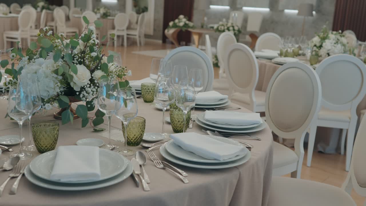 Round banquet table prepared with layered plates folded napkins glassware and soft white floral centerpiece