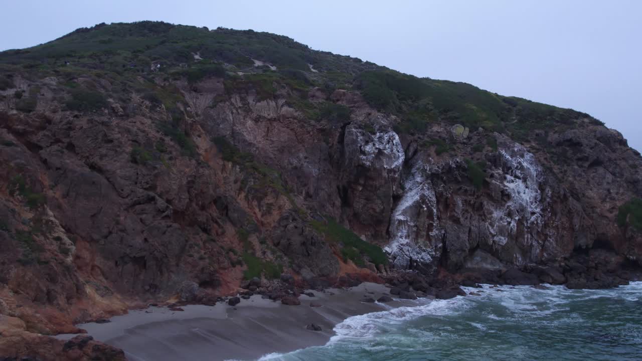 An up-close view of the rugged, rocky cliffs of Malibu, showcasing the dramatic landscape where the land meets the Pacific Ocean