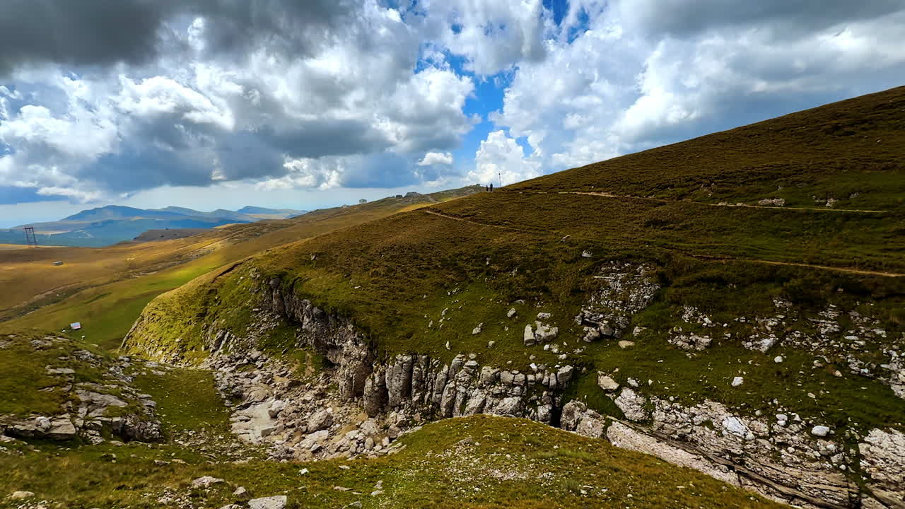 Verdi colline e scogliere rocciose dei Monti Bucegi. Vista panoramica delle verdi colline e delle scogliere rocciose sui Monti Bucegi con nuvole suggestive
