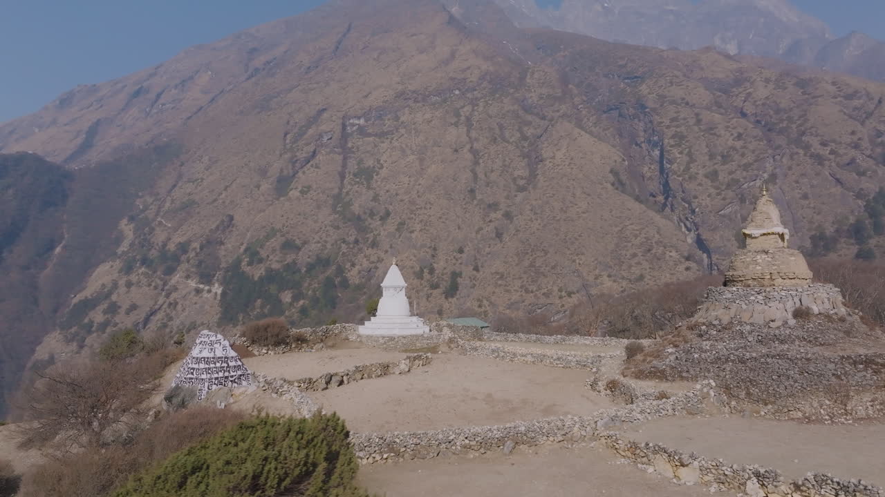 Ripresa con drone dell'Antica Stupa Buddista nel villaggio di Phortse, colline aride, terre secche, cielo sereno, nuvole sfocate, luce solare—segnali dell'impatto del riscaldamento globale e indicazioni per una cauta conservazione naturale