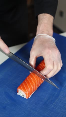 chef preparando un rollo de sushi de salmón