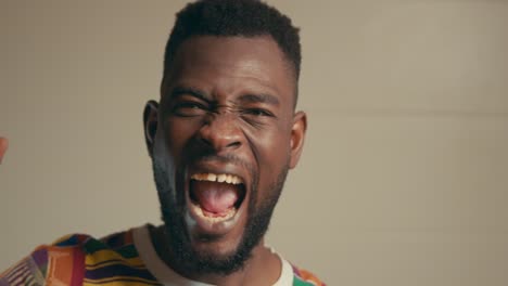 portrait of african american man wearing kente fabric shirt excitingly celebrating in slow motion