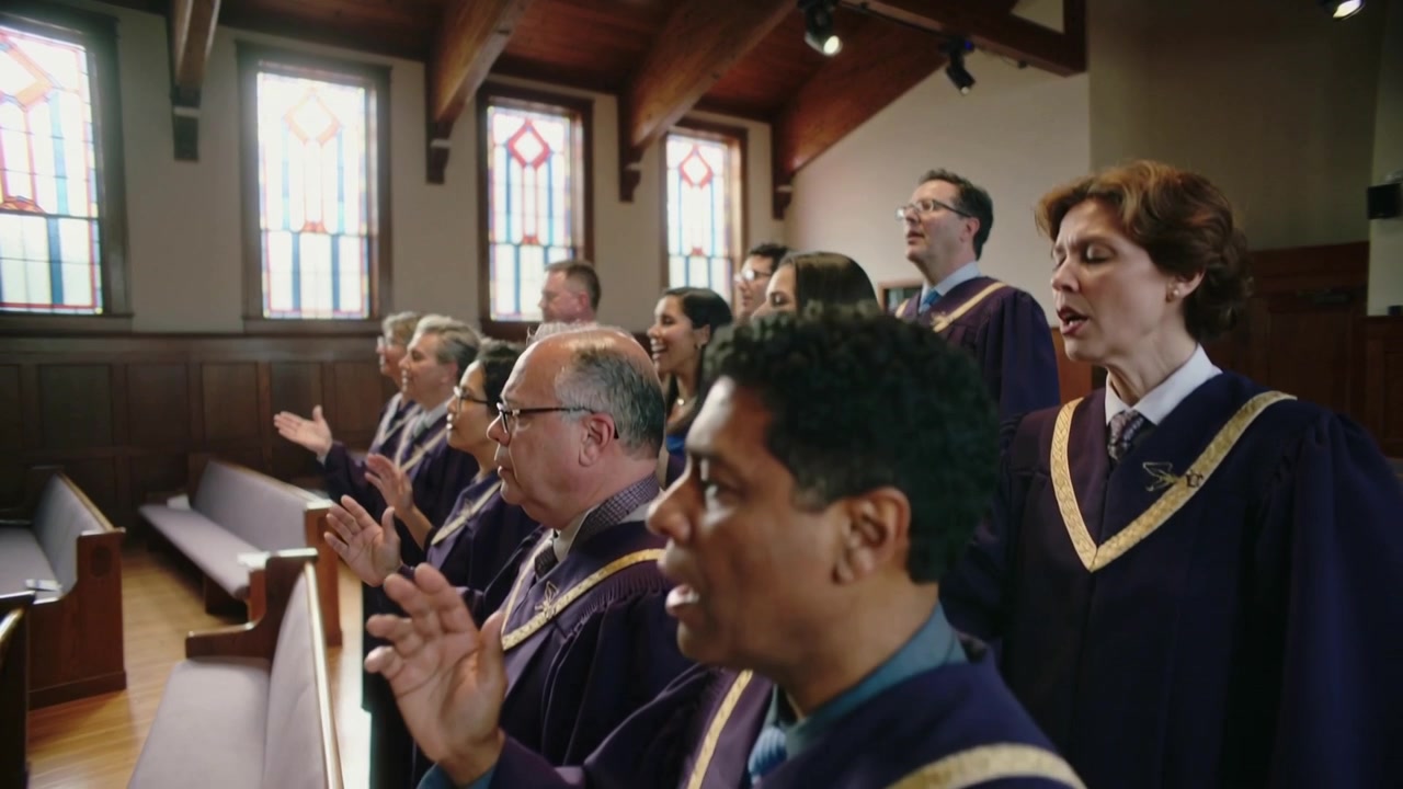 Singing church choir with camera panning, lifting hands and leading worship in church, purple robes