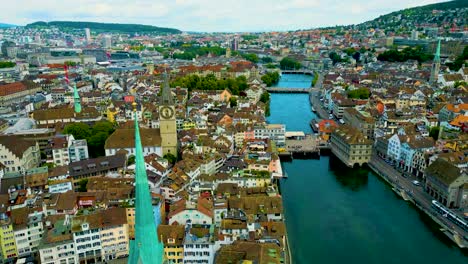 4k drone video of the historic predigerkirche and st. peter churches on the banks of the limmat river in downtown zurich, switzerland