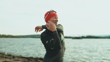 female triathlete in swimsuit warming up on lakeshore