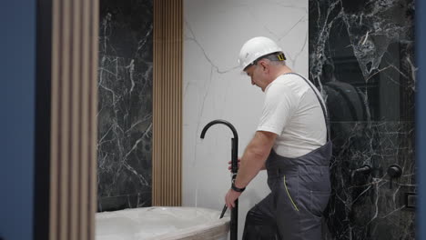 plumber checks the operation of the faucet and shower head in the bath