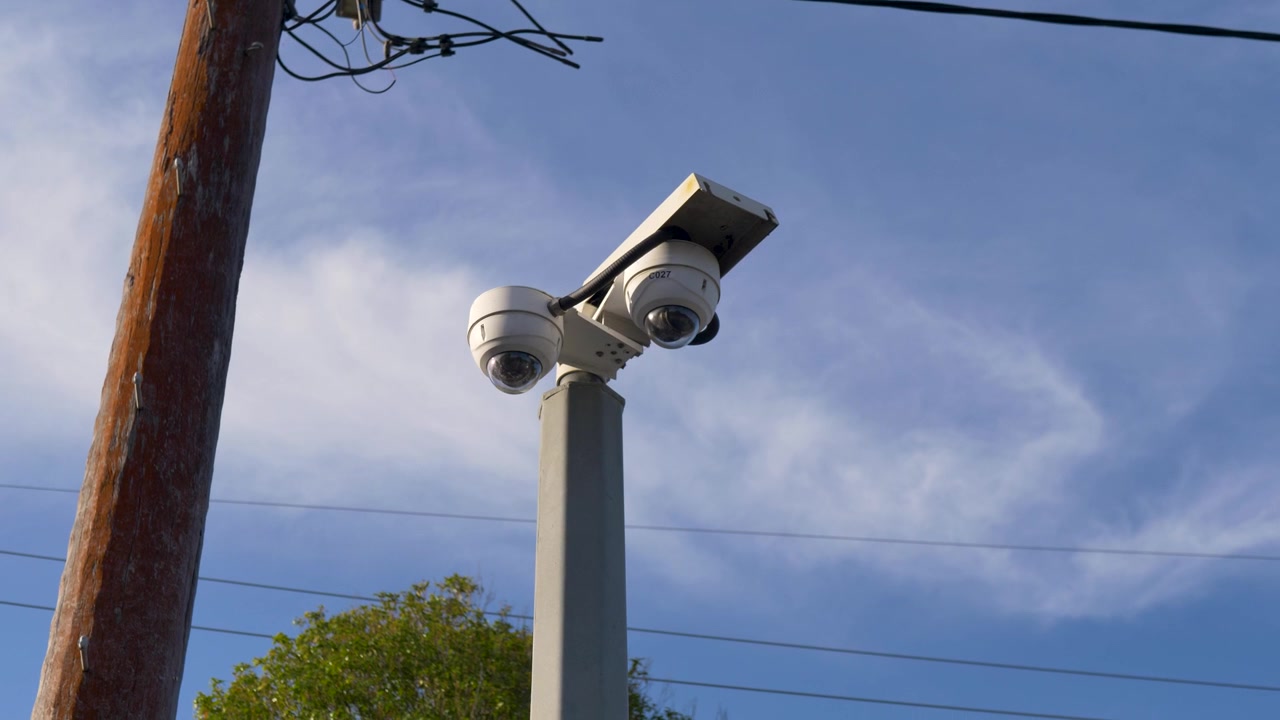 Slow motion landscape view of a dome security camera surveillance system mounted on a metal pole at a public train station plaza for community safety at Central Coast Australia public infrastructure