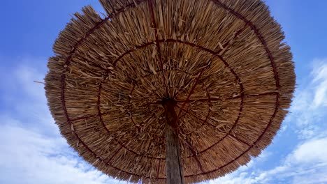 Wide-angle-shot-of-wattled-straw-beach-umbrella-against-blue-sky-background