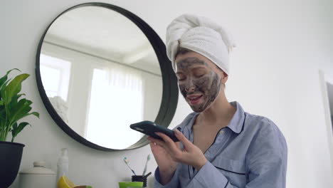 female with facial mask using a smartphone and talking