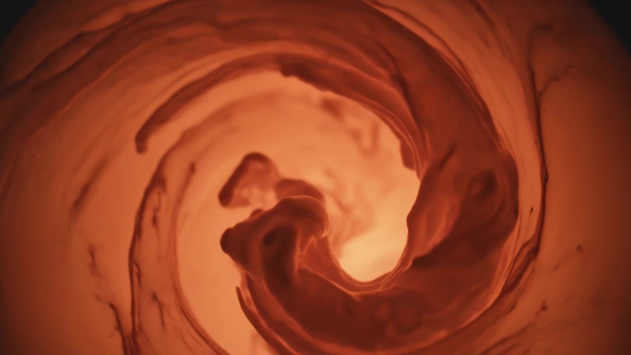 Lingue di colorante iniziali che si avvolgono verso l'interno, formando un vortice rotante che si avvolge a spirale attorno a un nucleo illuminato per la miscelazione.