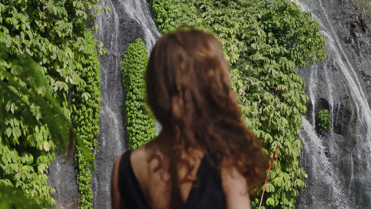 Woman Looking at Beautiful Tropical Waterfall in Lush Jungle