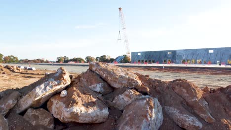 una toma de un dron que asciende y revela una grúa de servicio pesado que levanta un panel de concreto para colocarlo en su lugar
