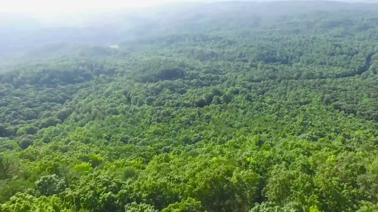 dron volando lentamente sobre algunos árboles y montañas en portugal