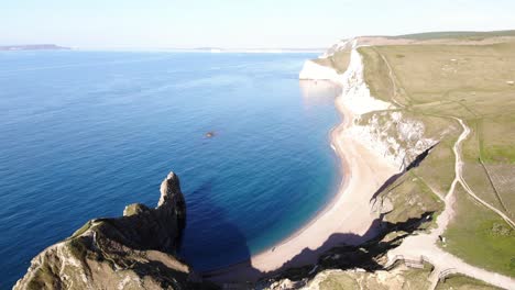 Luftaufnahme-Des-Sonnigen,-Leeren-Strandes-Neben-Sanften-Hügelklippen-Bei-Durdle-Door-In-Dorset