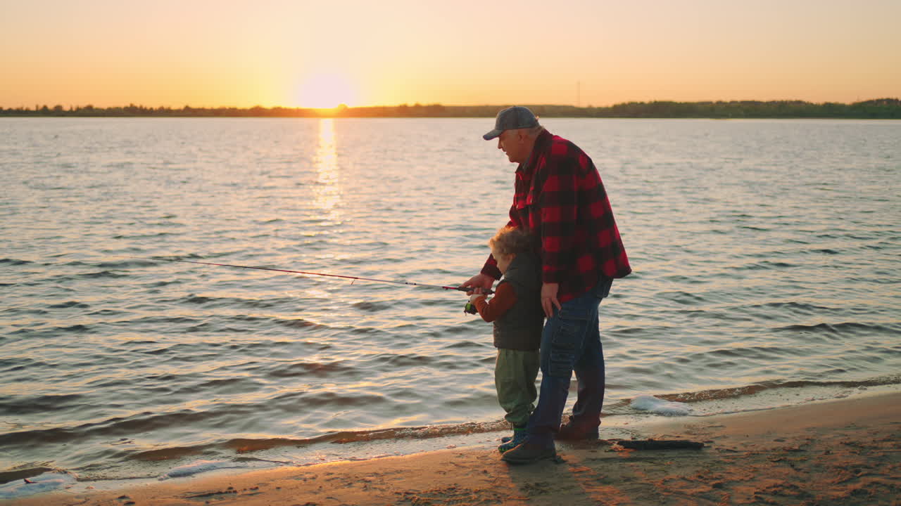pescando en la orilla de un río o lago el abuelo y el nieto están atrapando peces con la caña de pescar