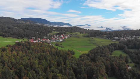 drone flies toward small slovenian mountain village sentviska gora on late summer day