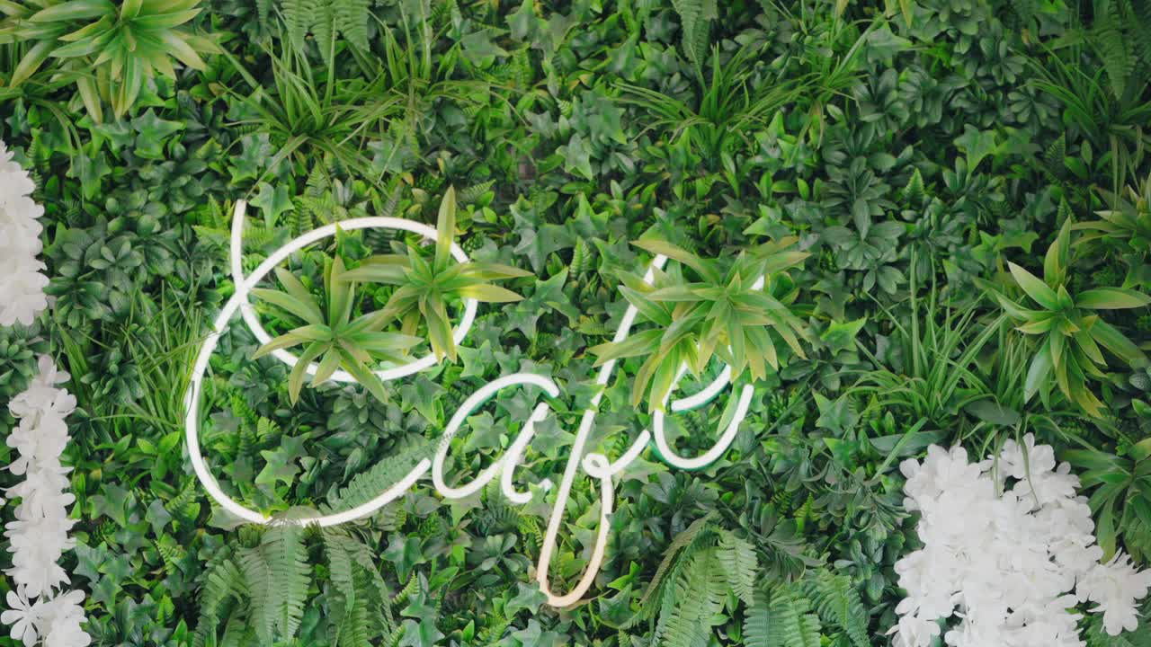 Insegna al neon di un caffè su parete verde lussureggiante