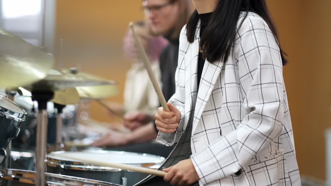성인 젊은 남녀들은 학교에서 드럼을 연주하는 법을 배니다.