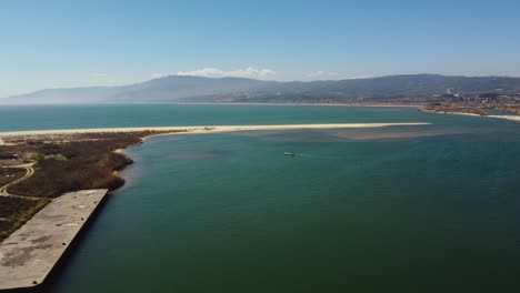 aerial of stunning lagoon next to the coastline with small boat on a sunny day.