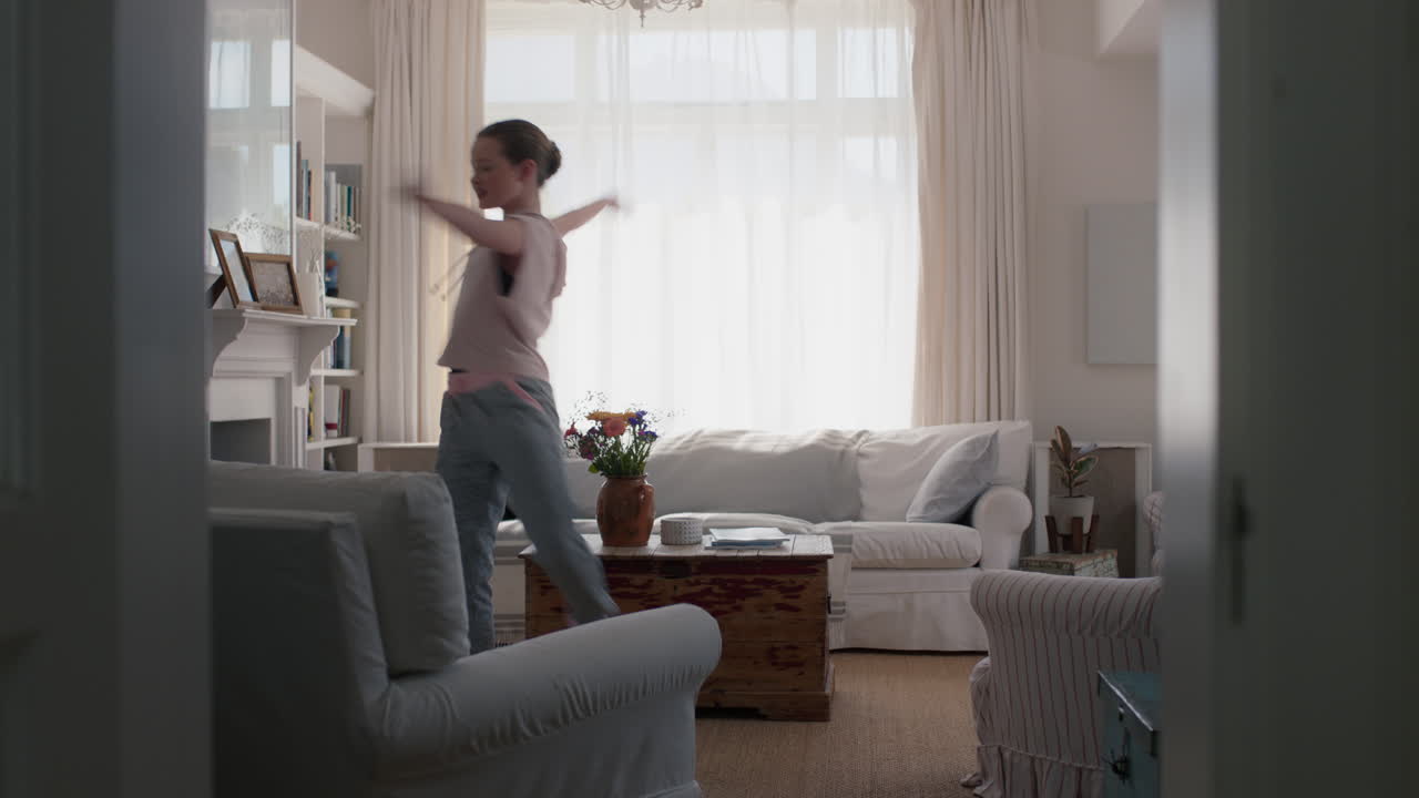 beautiful teenage girl dancing at home practicing ballet dance moves having fun rehearsing in living room