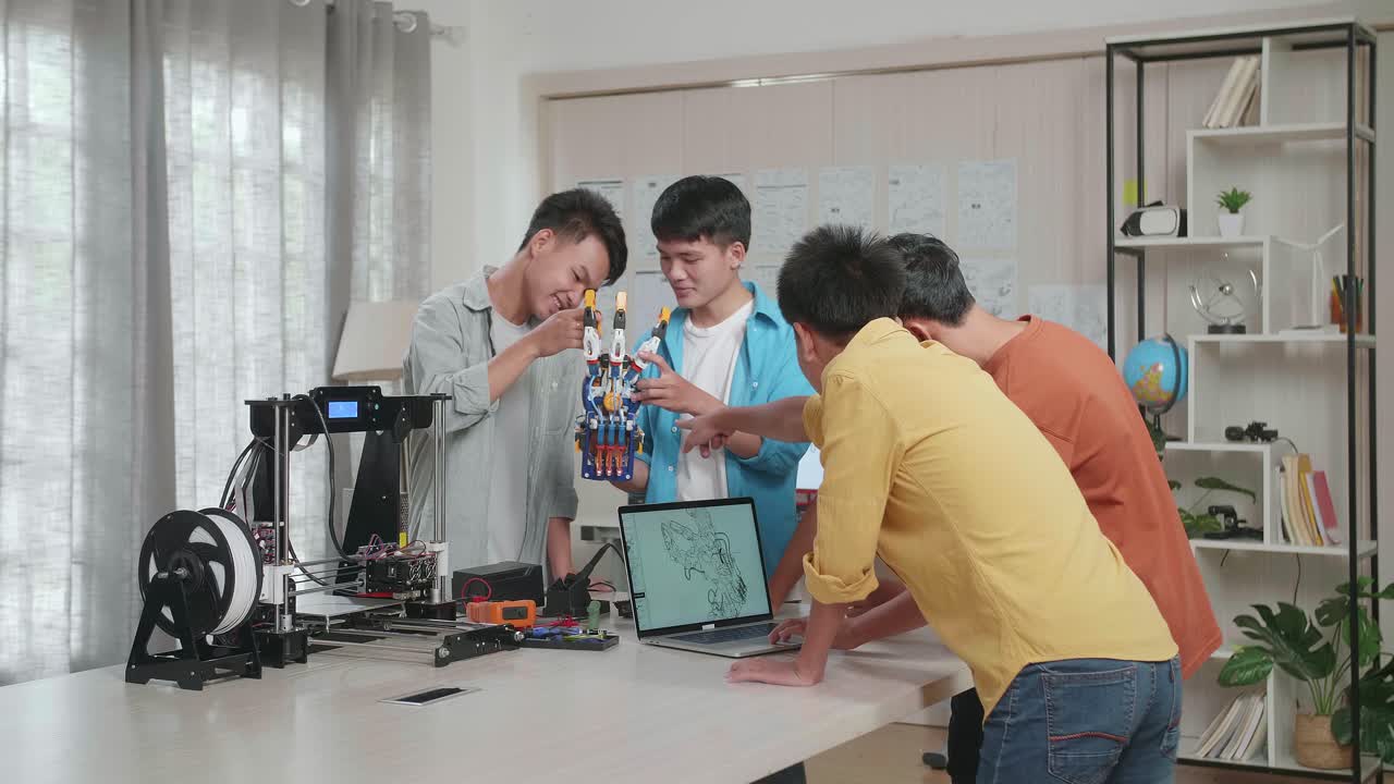 3d 프린팅으로 사이보그 손을 집에서 작업하는 젊은 아시아 소년 그룹, 세 소년이 노트북에서 디자인하는 동안 두 소년이 서로 논의하는 동안
