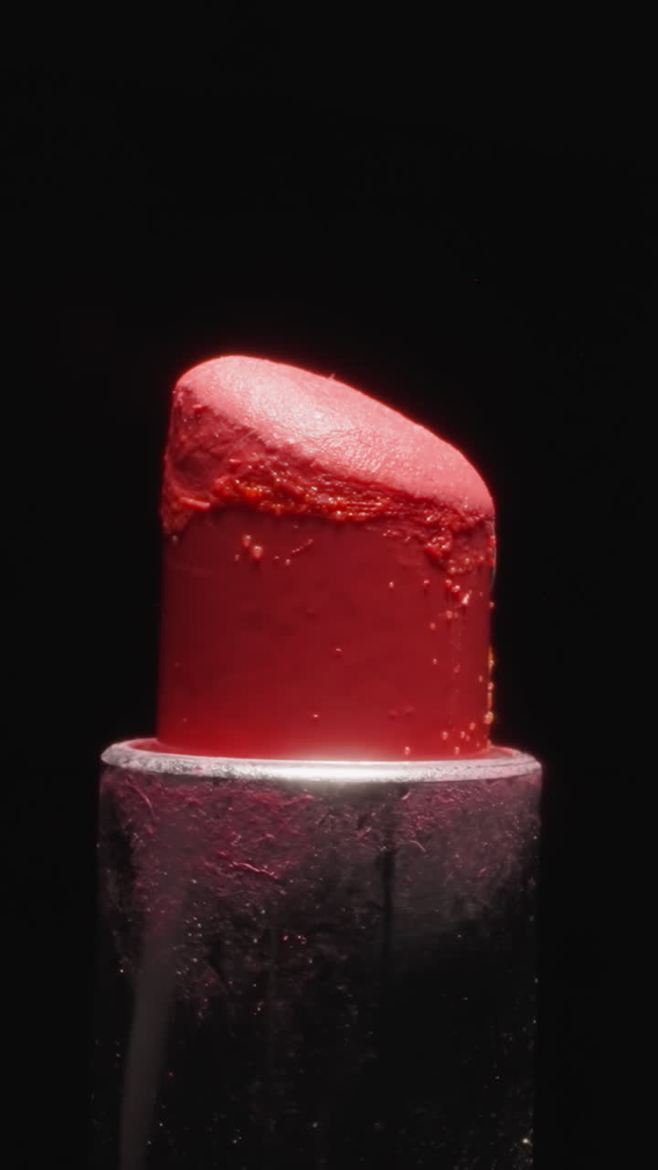 Used red lipstick texture for evening makeup illuminated with bright light on black background. Vibrant cosmetic product for painting lips macro