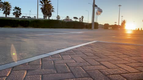 Experience-the-beauty-of-a-huge-sunrise-over-an-asphalt-park,-with-flags-gently-swaying-in-the-wind