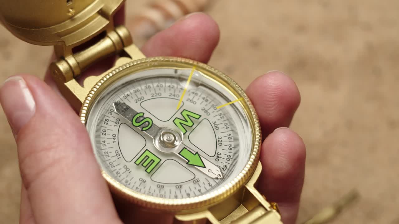 모래 배경에서 금색 나침반을 들고 있는 사람, 손바닥에 달린 금색 나선, 여행과 관광 개념, 항해