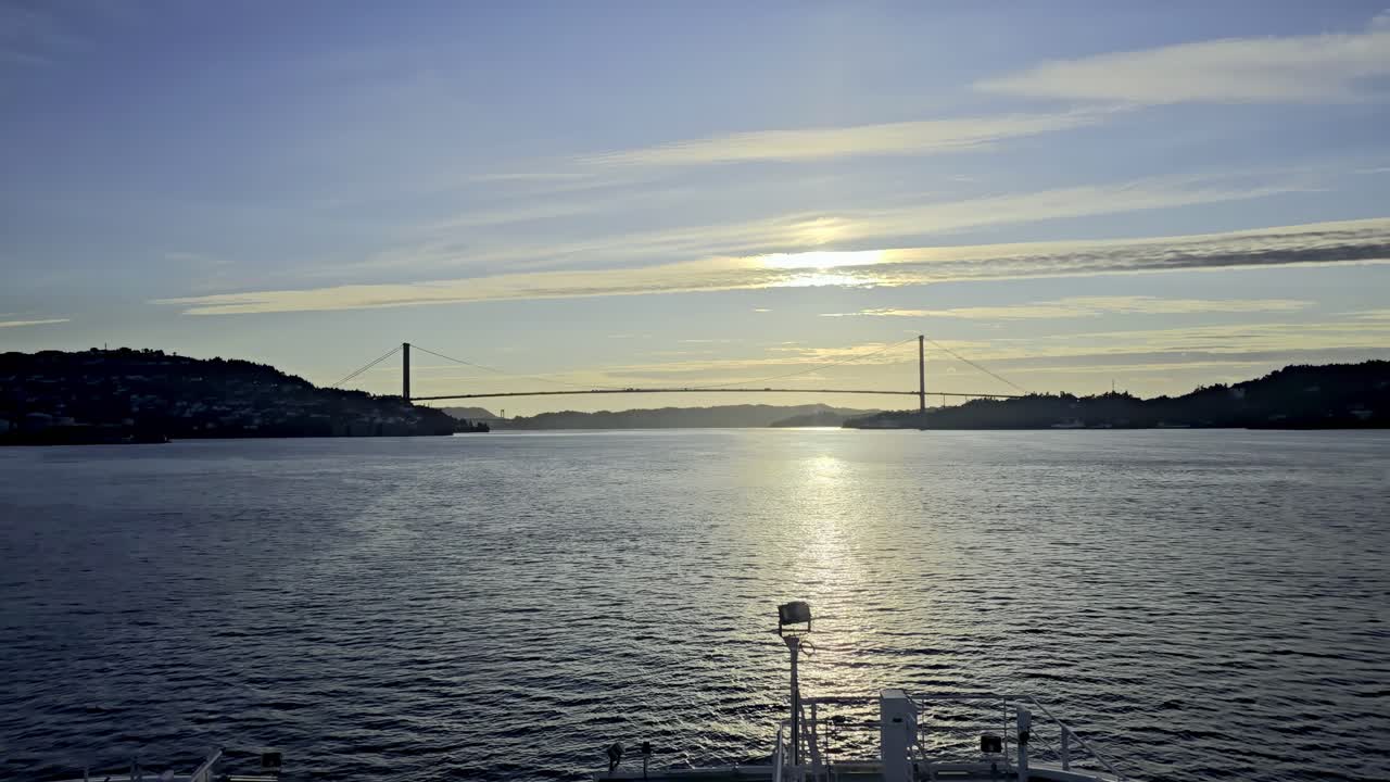 Forward view from vessel moving toward Askoy Bridge in evening light with reflections on water