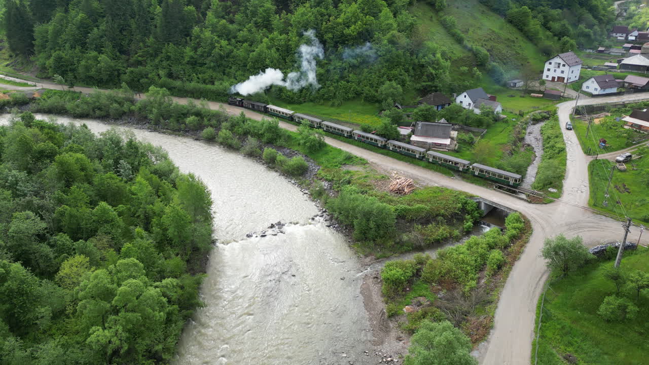 Aerial view Mocanita steam train traveling along Vaser river in Romania