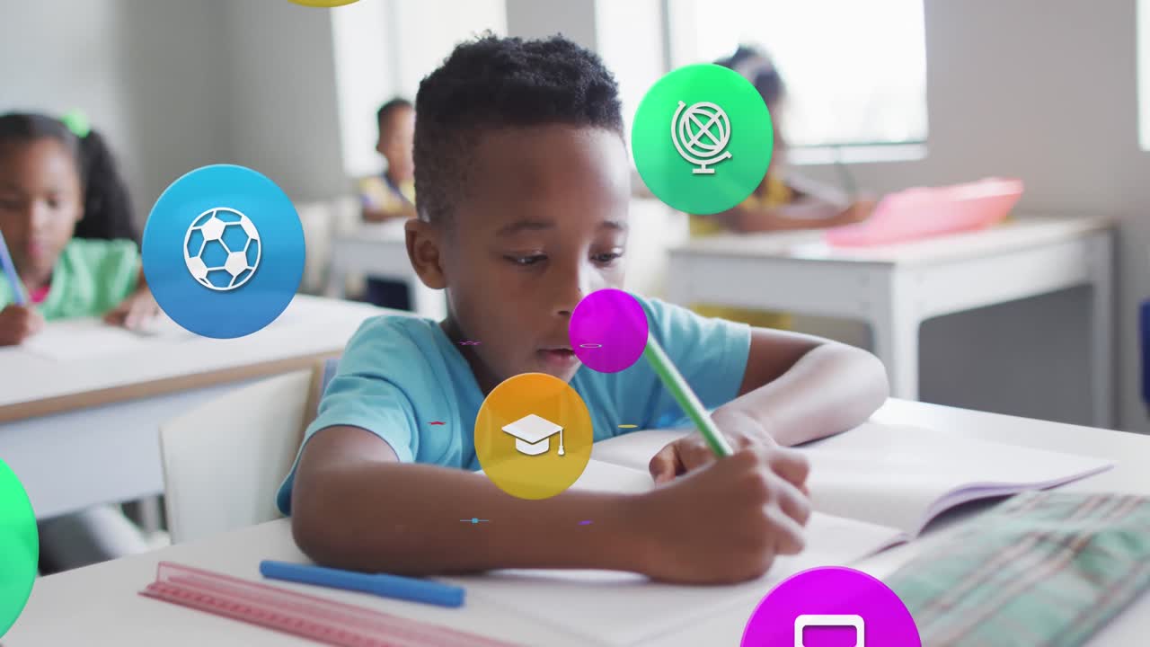 Animation of school icons over busy african american schoolboy working at desk in class